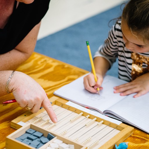Little girl writing and doing work with an educator.